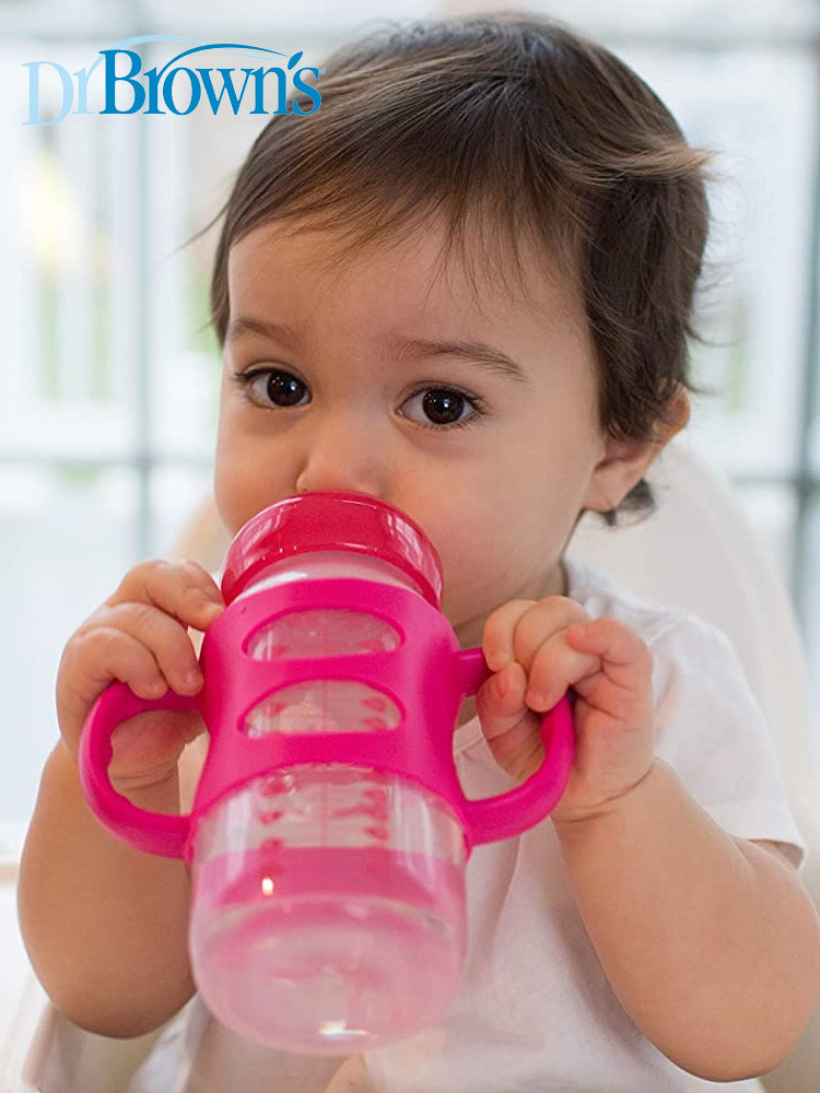 a toddler drinking from a pink dr browns options sippy spout bottle