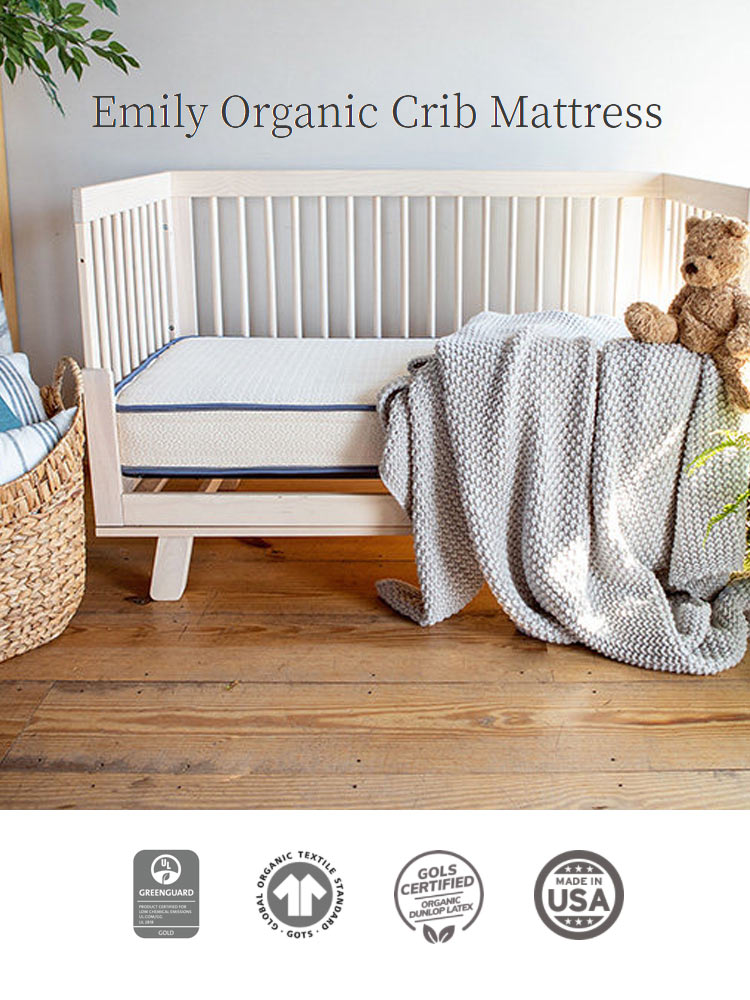 the emily organic crib mattress on a wooden floor with a blanket and basket