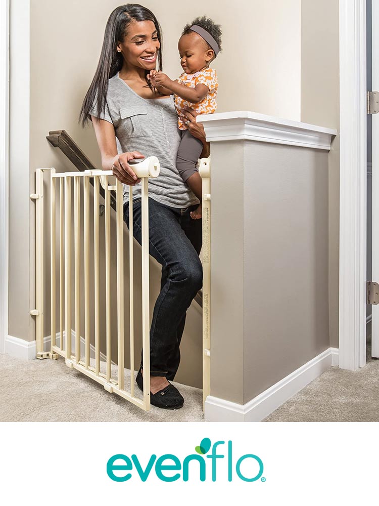 a mom walking up stairs while carrying a baby and opening the evenflo gate