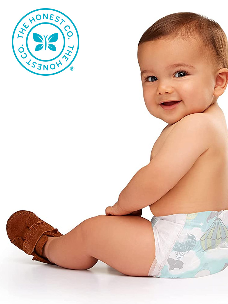 a baby sitting and looking at the camera wearing an honest company diaper