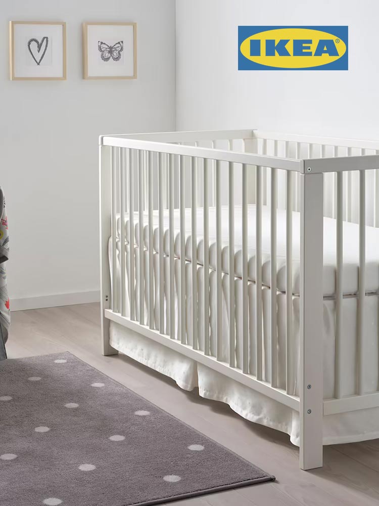 the ikea gulliver crib in a nursery with kids art and a polka dotted rug