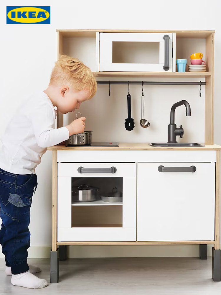 a boy playing with the ikea duktig play kitchen