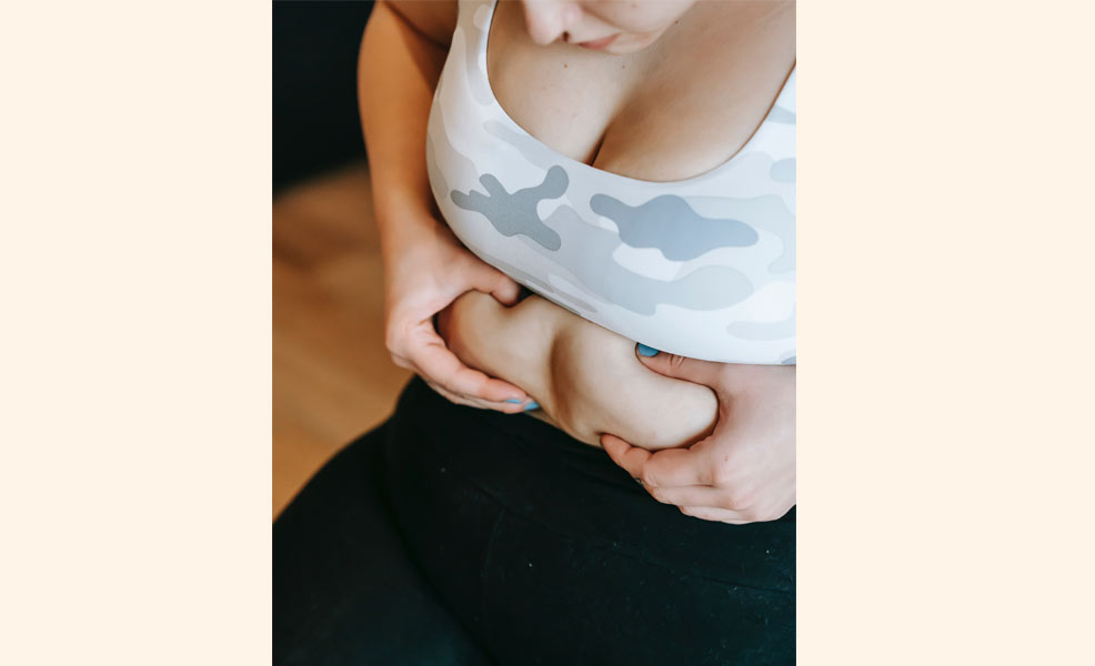 woman squeezing her stomach fat post partum