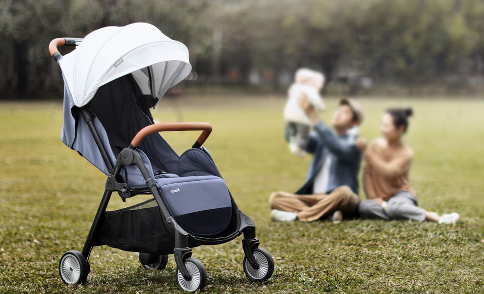 the besrey lightweight stroller in a park with parents playing with child in background