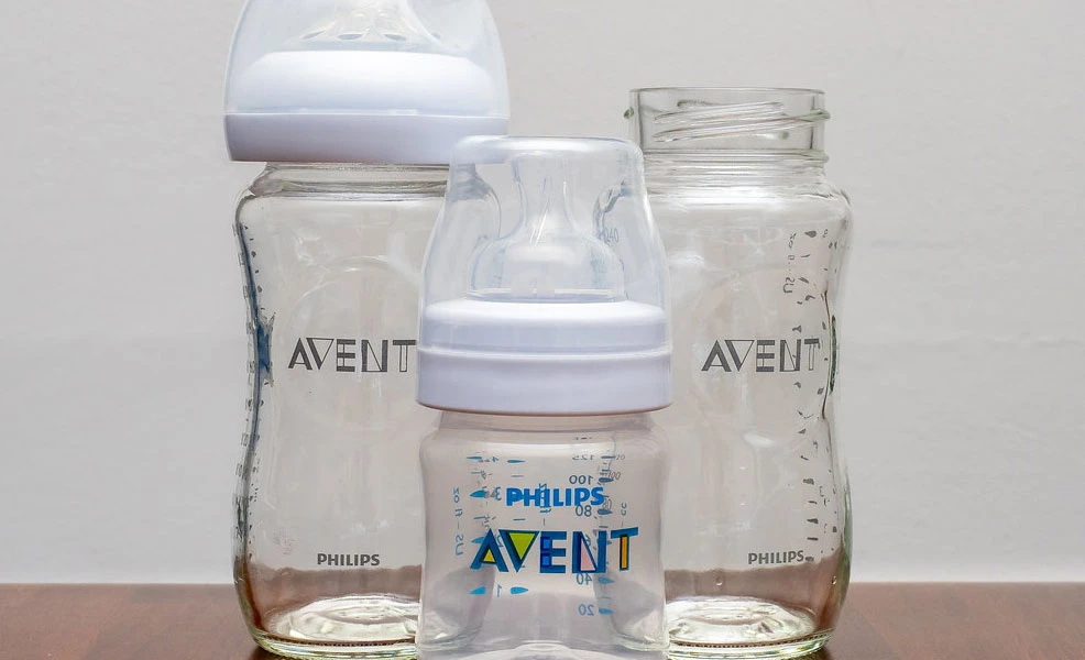 three Philips AVENT baby bottles on a kitchen counter