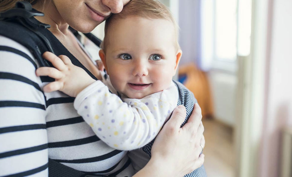 a mother carrying a baby in a cheap baby carrier