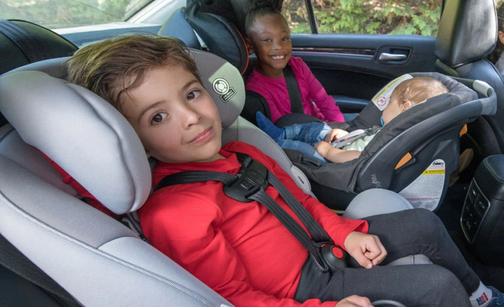 Mother checking car seat fit for her baby in the back seat of a car