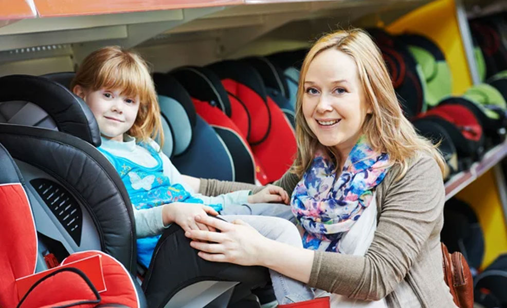 mom trying out a car seat with child