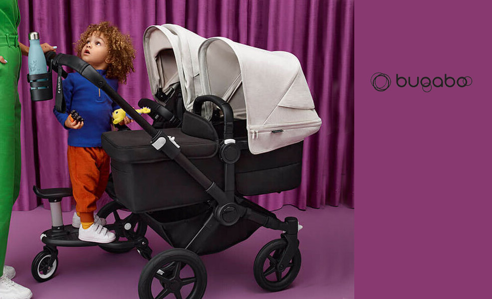 baby and toddler in a double stroller by bugaboo