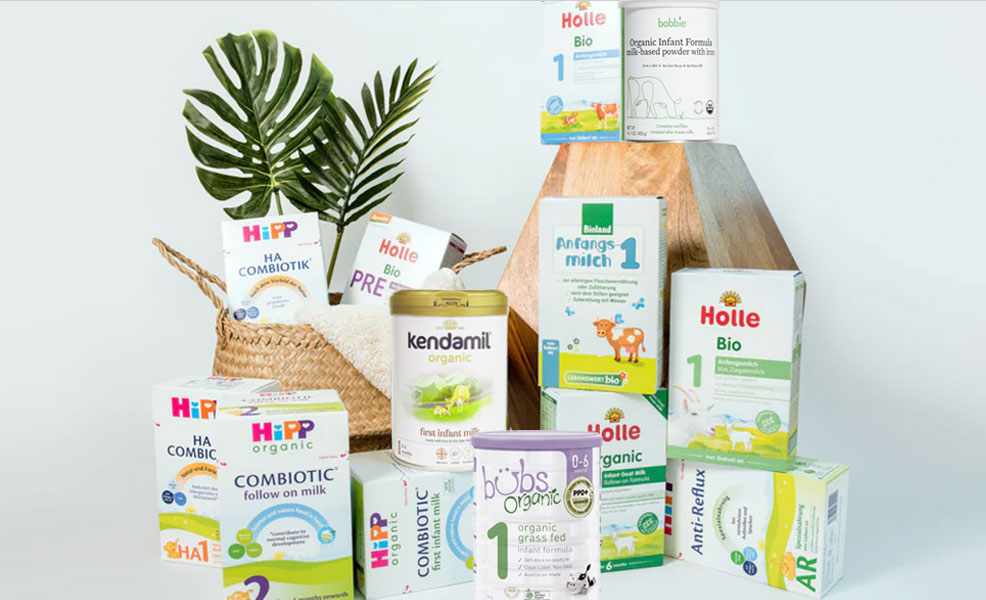 assortment of organic baby formulas atop wooden pedestals with a plant in the background