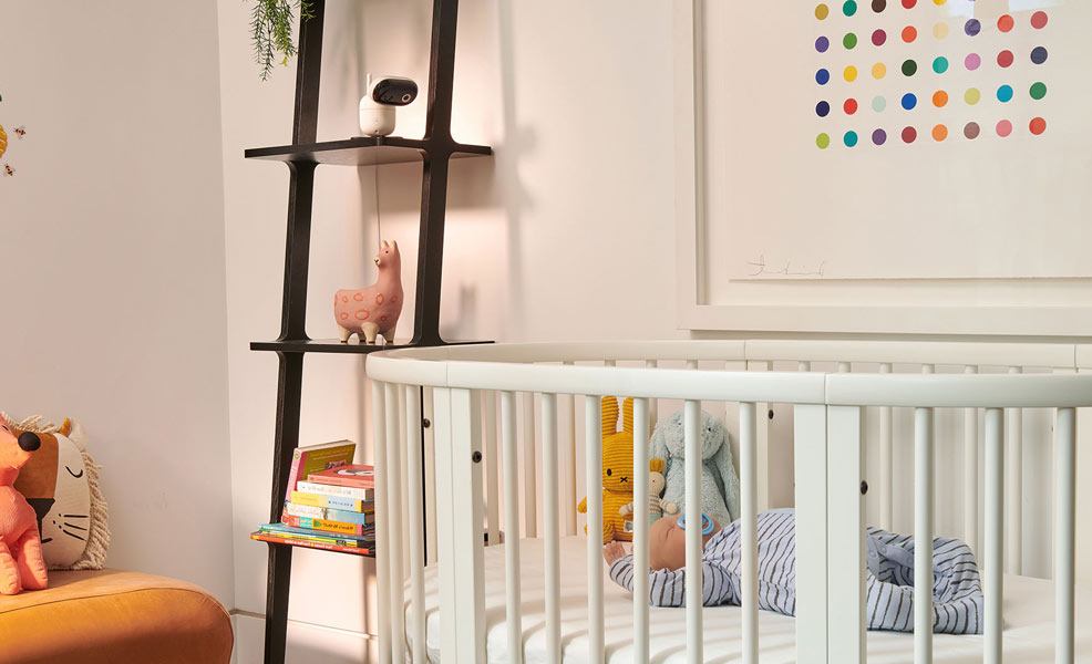 the motorola pip1510 connect baby monitor on a shelf next to a crib with a sleeping baby