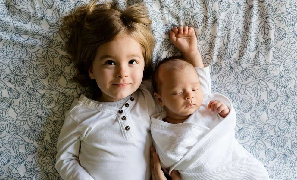 toddler and baby sleeping on a newton crib mattress