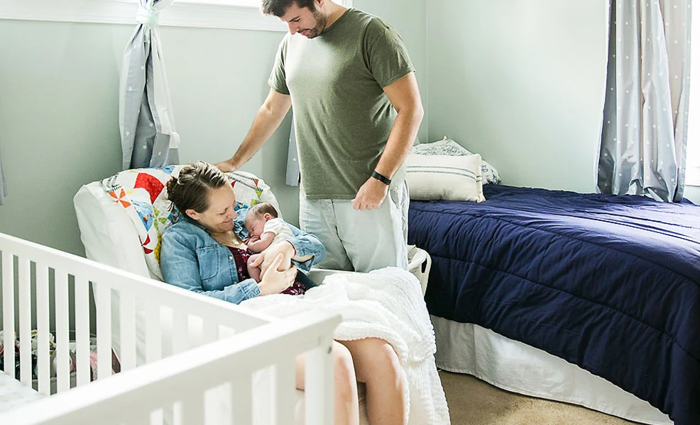 mom holding baby while rocking in nursery chair