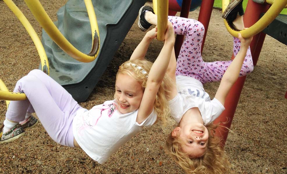 two kids playing outside on outdoor toys