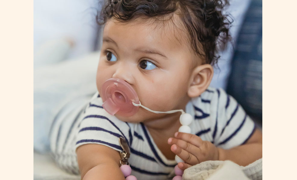 baby boy on his stomach with a pacifier in mouth