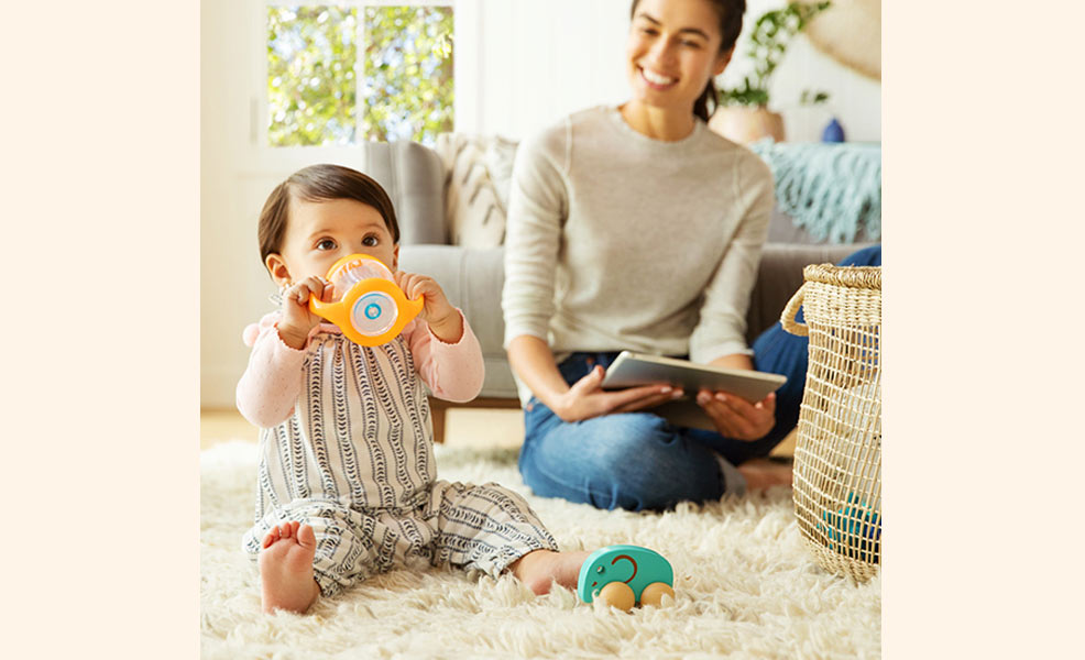 toddler drinking from sippy cup with mom watching