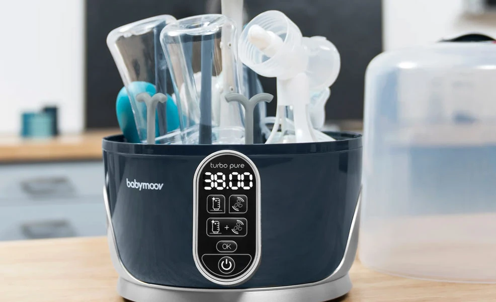 the babymoov turbo pure bottle sterilizer on a kitchen counter and filled with baby bottles