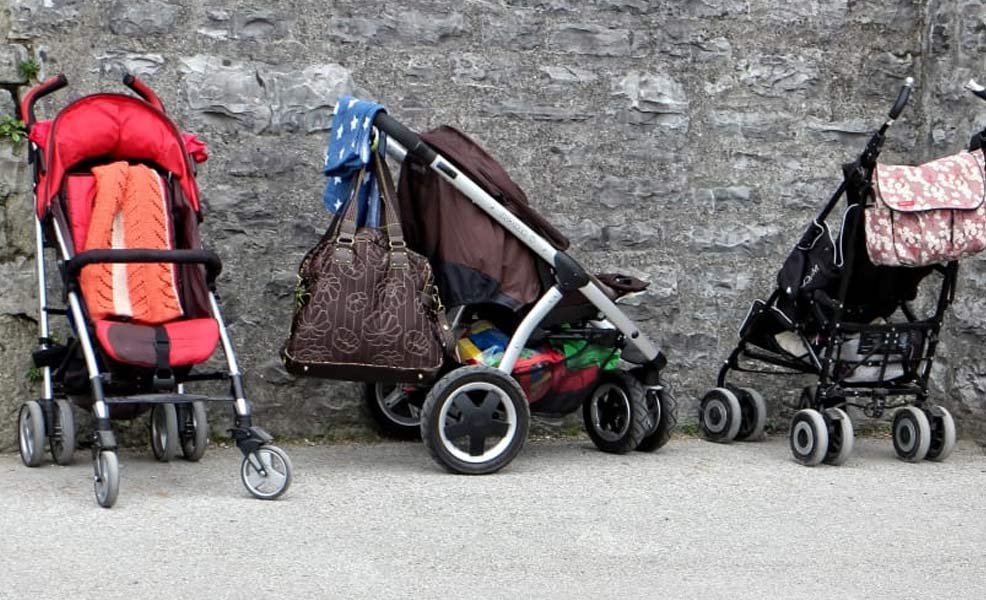 several strollers outside against a stone wall