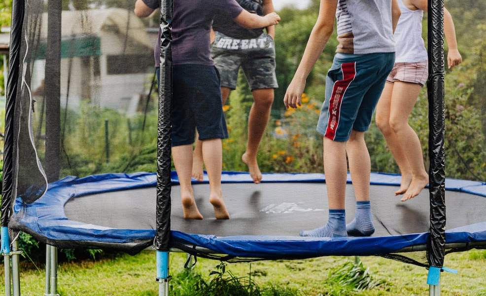 four children jumping on a large trampoline together