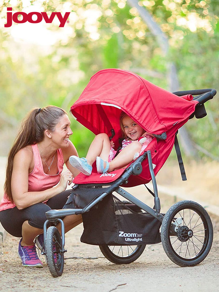 mother kneeling down and smiling with her toddler who is sitting in the joovy zoom 360 stroller