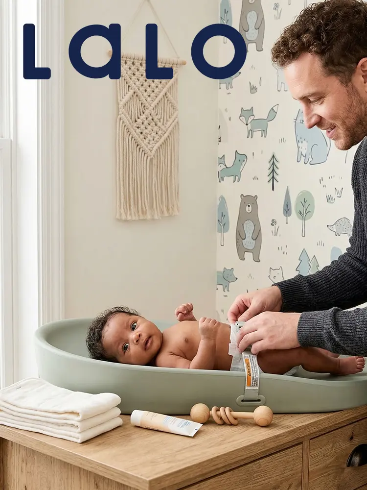 a dad changing a babys diaper on the Lalo Wipeable Changing Pad in a nursery background
