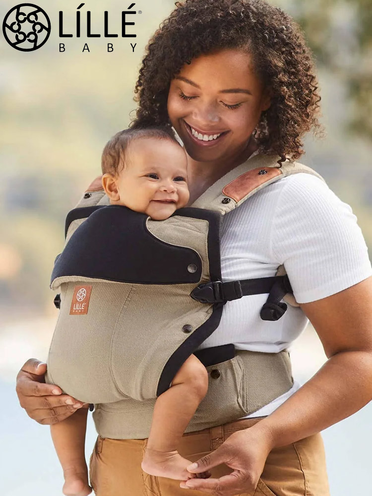 a woman carrying a baby in a lillebaby elevate baby carrier