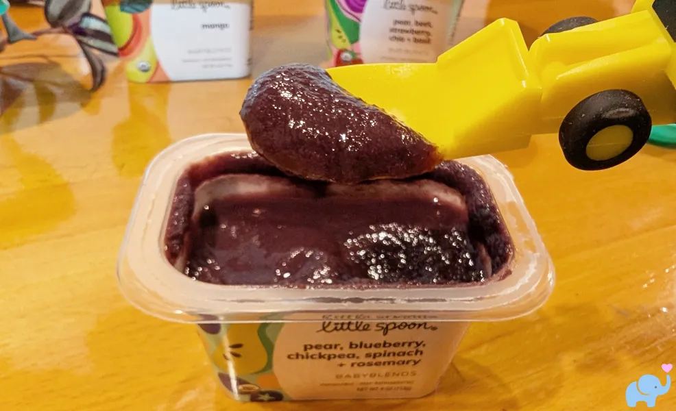 Little Spoon pear blueberry chickpea spinach rosemary baby food with spoon scooping puree