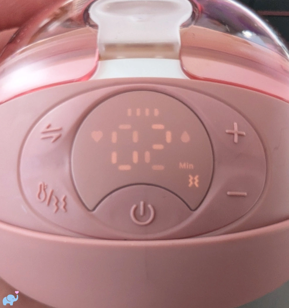 control panel and screen on the Momcozy Wellness 1 breast pump showing buttons for power heat massage both heat and massage intensity and pumping modes