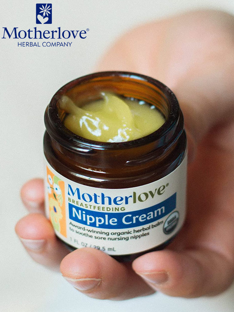 a hand holding an open jar of motherlove organic nipple cream