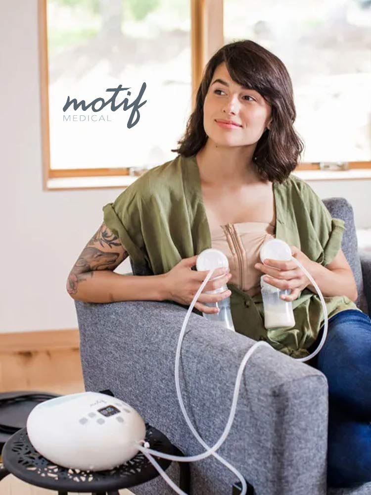 woman sitting on couch using the motif luna double breast pump