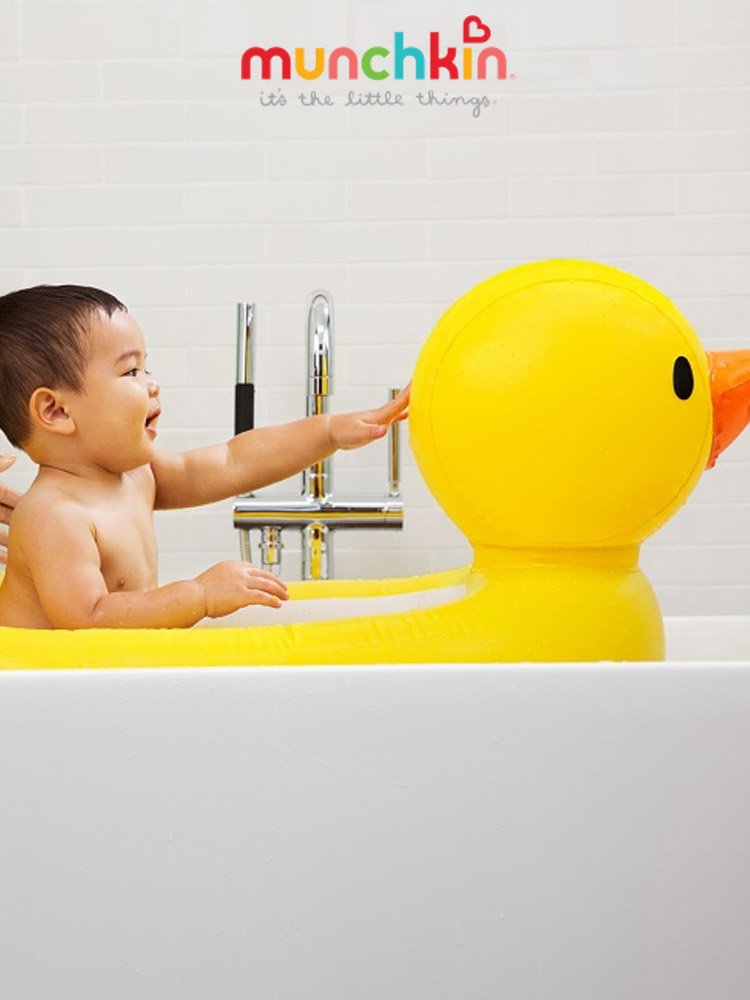 a baby boy sitting and getting a bath in the munchkin duck inflatable bathtub