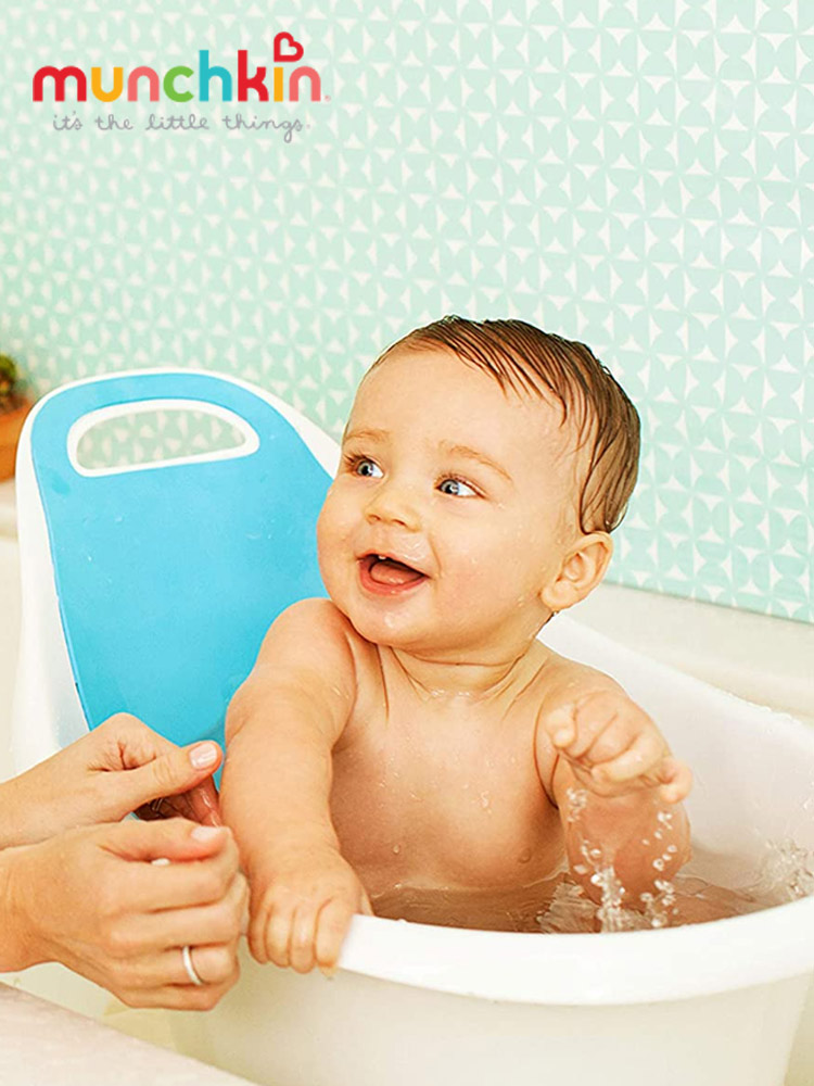 a smiling baby boy taking a bath in the munchkin sit and soak tub
