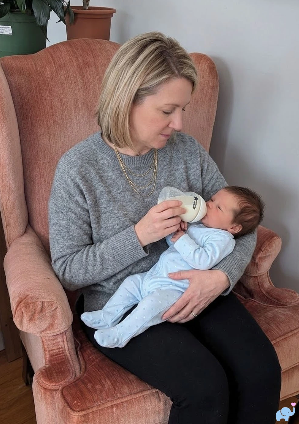 mom sitting in a chair feeding a baby with a bottle prepared with Nara Organics formula