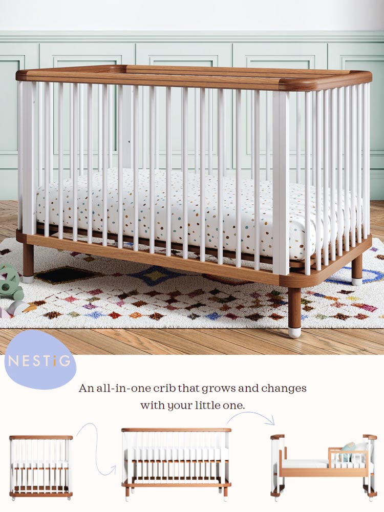 the nestig cloud crib with white rails and wooden trim with a polka dotted mattress in a nursery with a colorful rug
