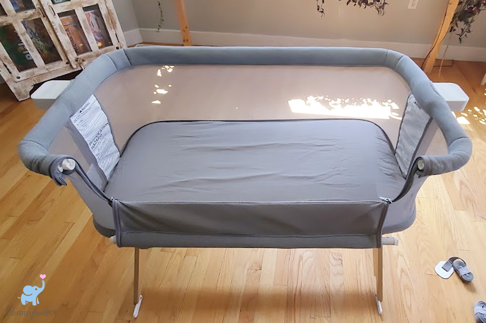 a side view of the newton bassinet with a baby sleeping inside