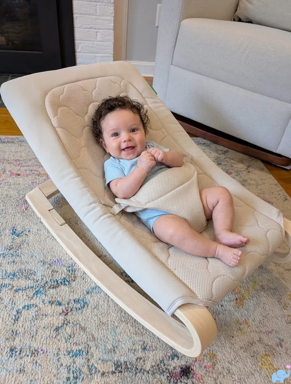 six month old baby smiling while sitting in the Newton Baby Rocker