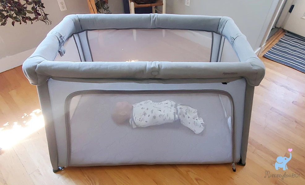 newton travel crib and play yard with a sleeping baby inside