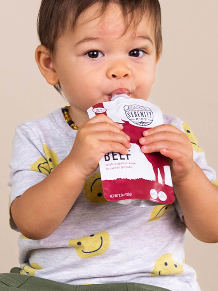 a baby boy eating serenity beef puree from a pouch