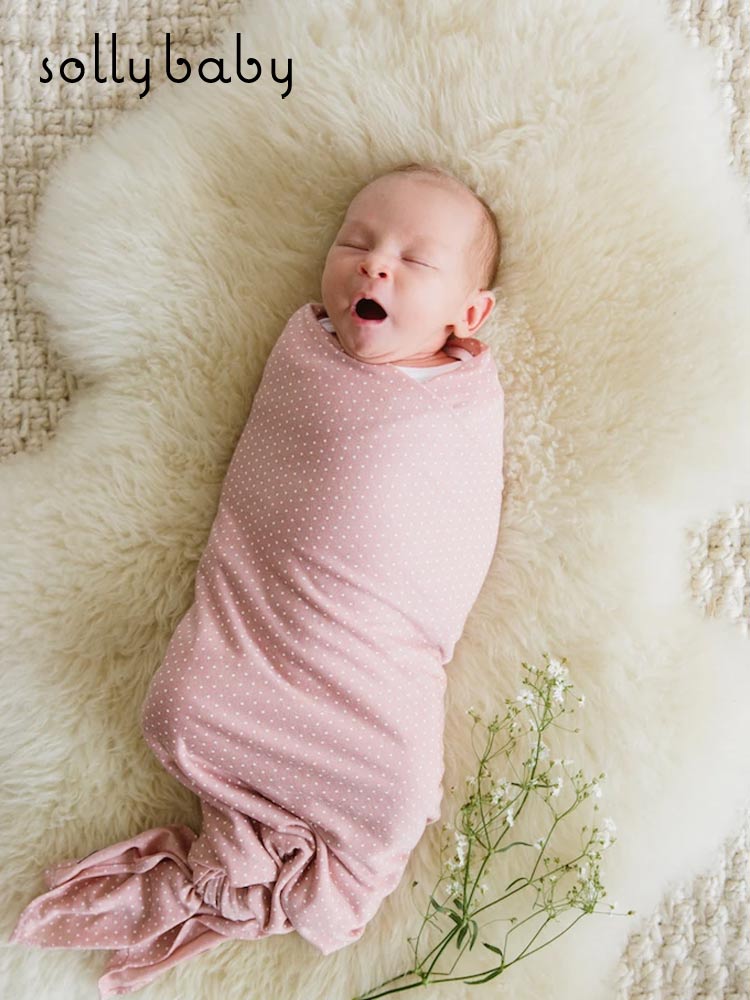 a yawning baby wrapped in a solly baby swaddle wrap