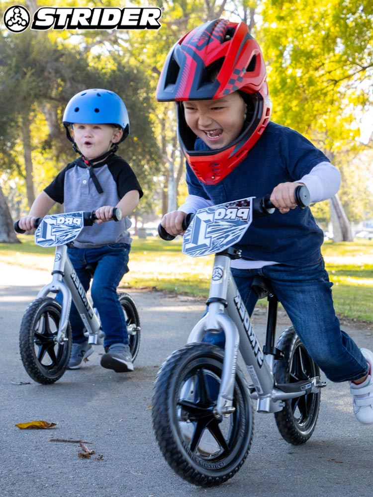 two kids riding strider bikes in the park