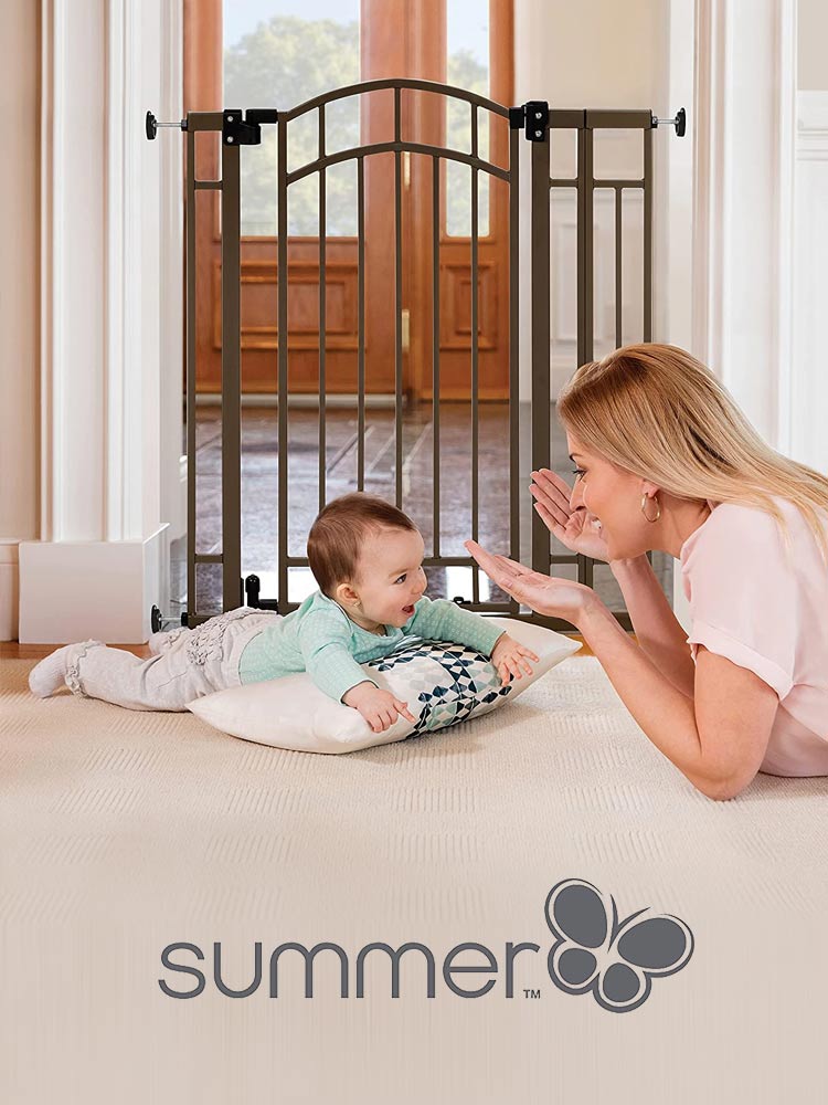 a mom playing peek a boo with a baby doing tummy time in front of a summer infant baby gate