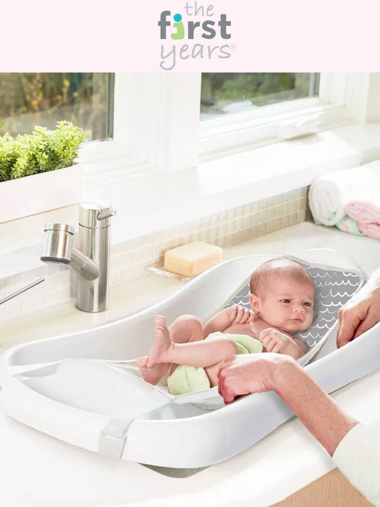a parent bathing a baby in a first years sure comfort bathtub