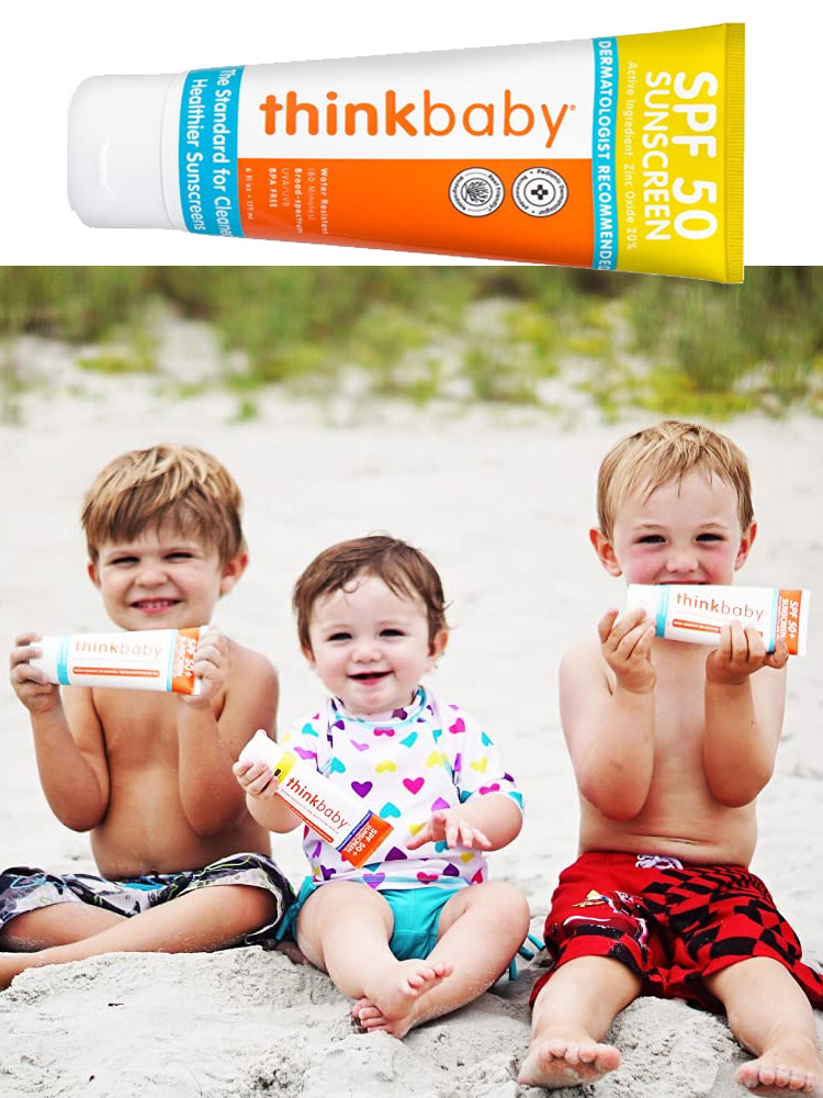 three children sitting on the beach and holding thinkbaby sunscreen
