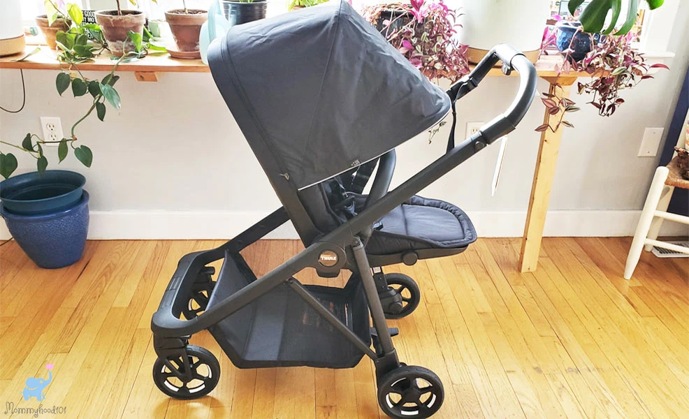 thule shine stroller with canopy open on hardwood floor with plants in background