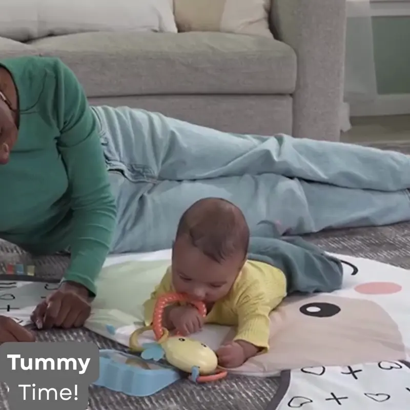 babies playing and doing tummy time on a play mat with toys and mirror