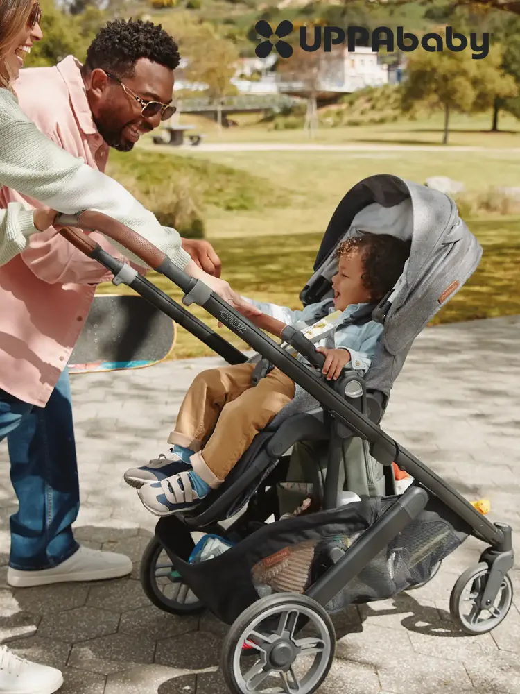 parents pushing a toddler boy in an UppaBaby Cruz v3 Stroller