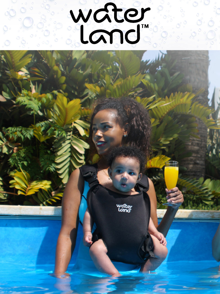 a woman carrying a baby in a waterland baby carrier while holding a drink in the pool
